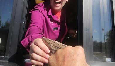 An employee hands a customer's order through the drive-through window of Panera Bread