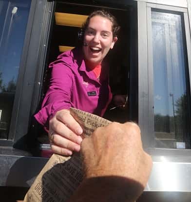 An employee hands a customer's order through the drive-through window of Panera Bread