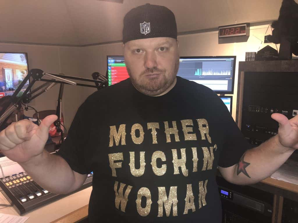 Jason with his hands up wearing a shirt that says mother fuckin woman