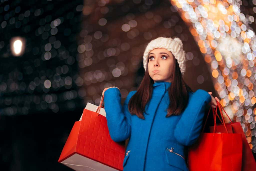 A lady looking stressed holding multiple shopping bags,