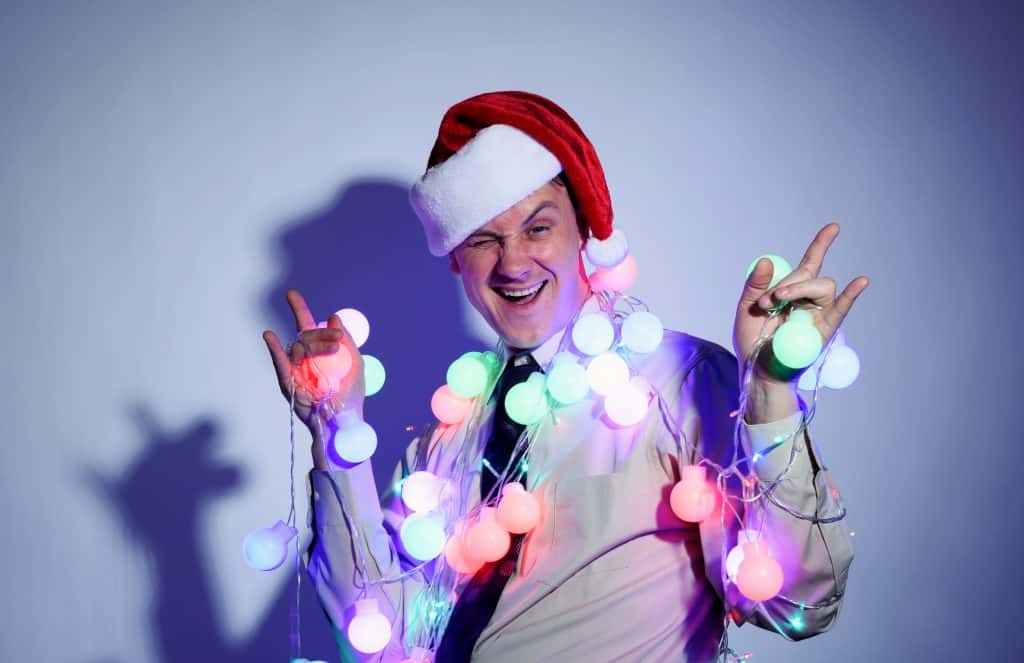 Shutterstock Image of a guy in a Christmas hat with lights around his neck throwing up the rock on sign.