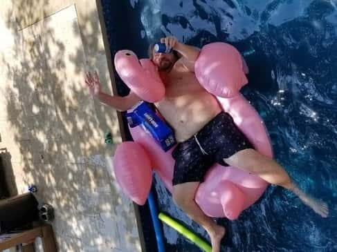 Jason in his pool with a pink flamingo