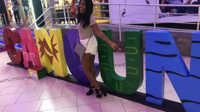 New producer Imari in front of a Cancun sign.