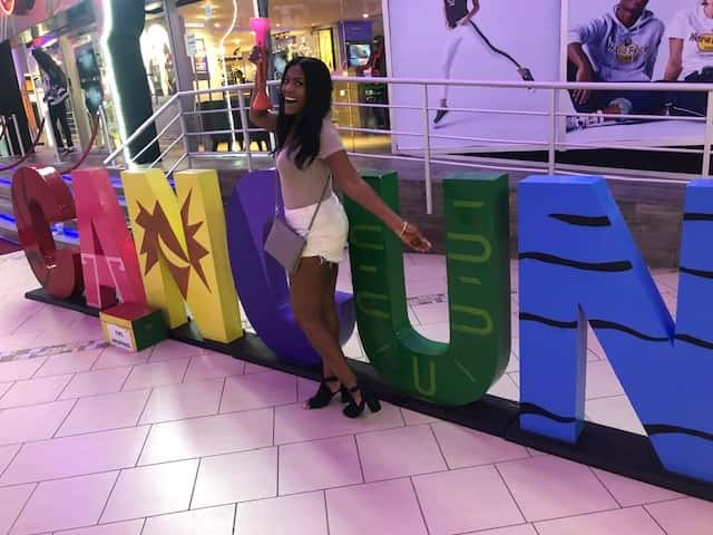 New producer Imari in front of a Cancun sign.