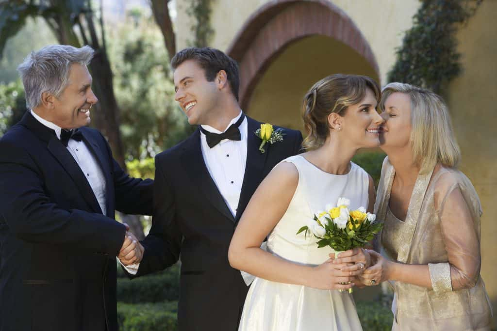 Groom and father of the bide talking along side bride and mother of the bride