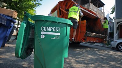 compost bin with garbage man behind loading truck
