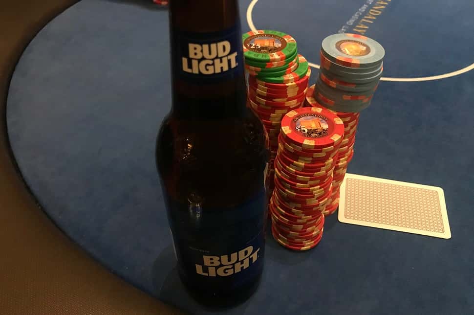 a bud light next to poker chips on a poke table