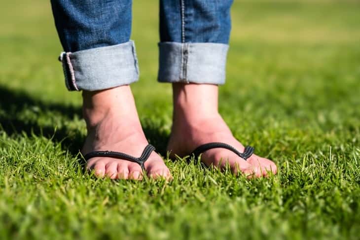 A guy in flip flops on the grass.