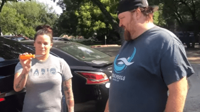 Deb and Jason with a screw driver in front of Jason's Tesla.