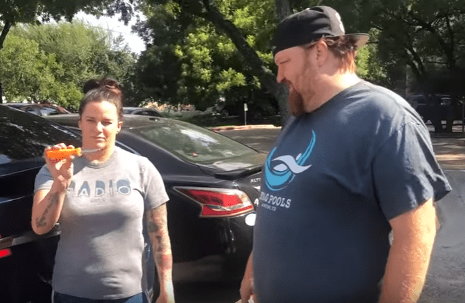 Deb and Jason with a screw driver in front of Jason's Tesla.