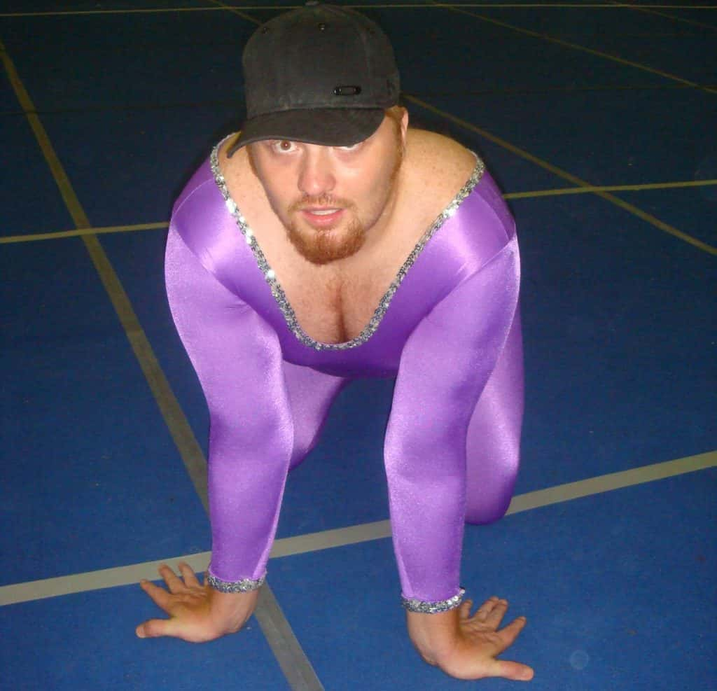 Jason dick posing in bright purple gymnasts leotard.