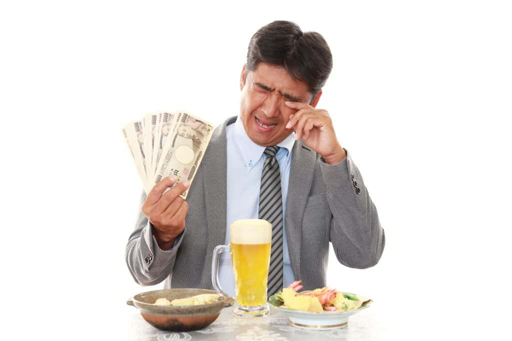 Shutter Stock Image of a guy with money in his hand and a beer crying at a dinner table