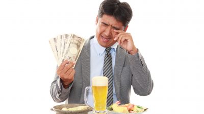 Shutter Stock Image of a guy with money in his hand and a beer crying at a dinner table