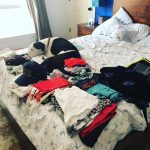 Blue boy using his camouflage tactics to come along Deb's vacation to Singapore.: Deb's dog Blue on her bed in a pile of clothes. 