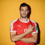 Luka Milivojević: Serbia Midfielder: Luka Milivojević: Serbia Midfielder showing off country patch in front of orange wall