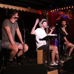 101X-Session With AJR: Jack from AJR with his hands up while Ryan and Adam look at him