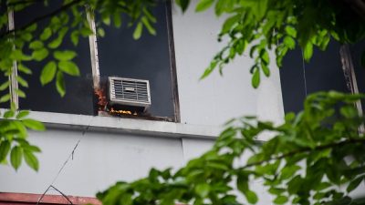 Getty image of Air conditioning unit on fire outside of a building
