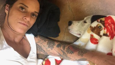 Deb and Blue after his acupuncture treatment laying down with a red blanket.