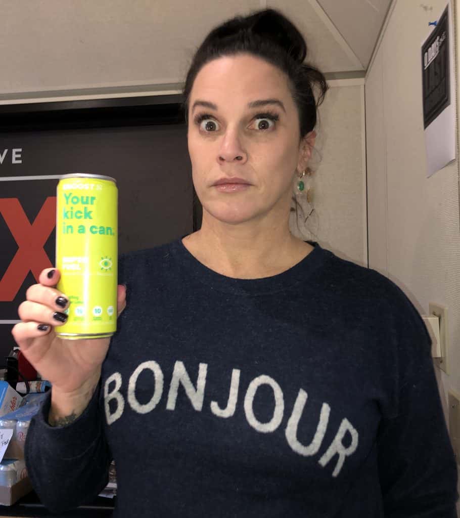 Deb holding up a can of eboost energy drink with a wide-eyed look on her face