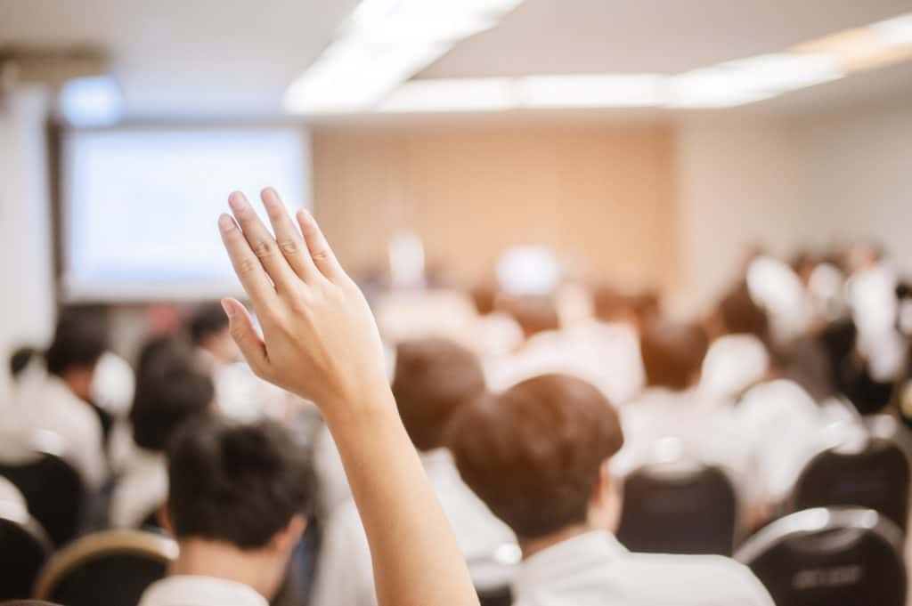 stock photo of someone raising their hand in a business meeting
