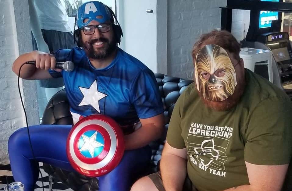 dave b dressed as captain america sitting next to Jason wearing a paper chewbacca mask