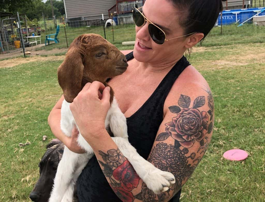 deb on a farm holding a goat in her arms