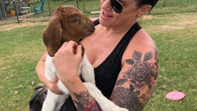 deb on a farm holding a goat in her arms
