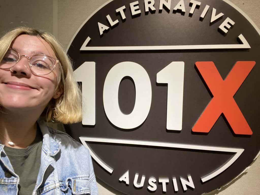 producer katy in studio posing in front of the 101X Logo