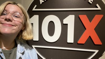 producer katy in studio posing in front of the 101X Logo