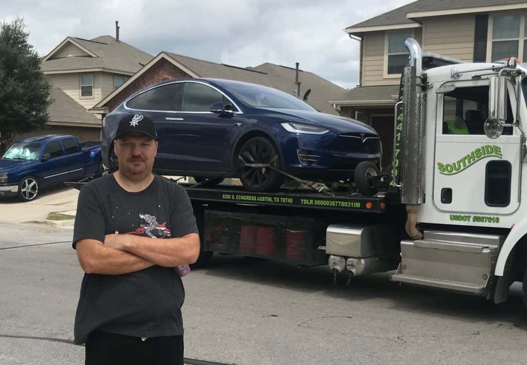 Jason looking agitated in front of his tesla being loaded onto a tow truck