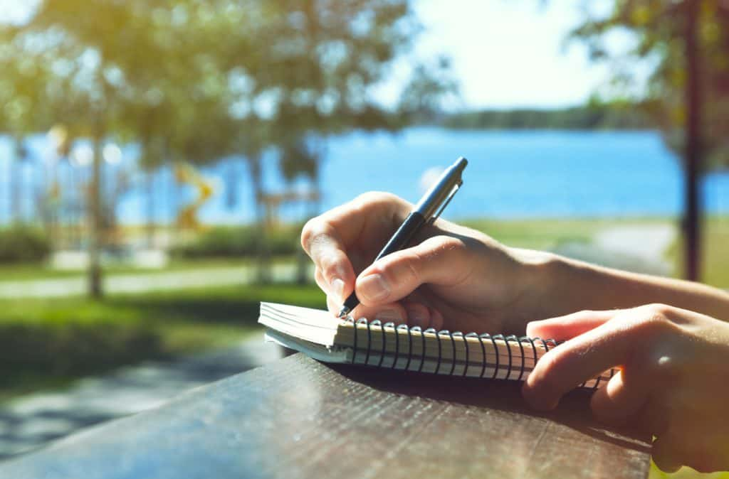 a stock photo of someone writing in a diary outside