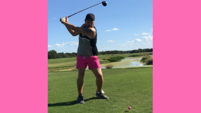 Jason teeing off on the golf course wearing pink short shorts and a tank top