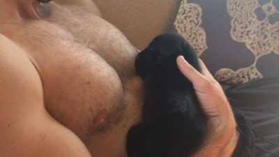 deb's foster puppy django being held be a shirtless Jeff