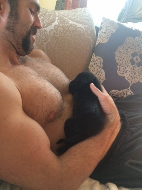 deb's foster puppy django being held be a shirtless Jeff