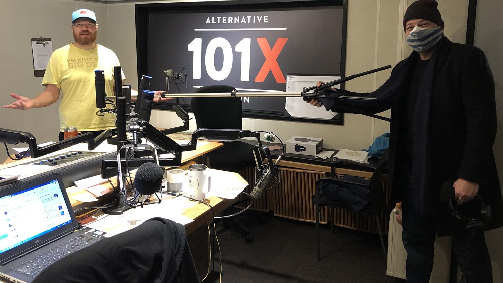 Andy langer in studio holding up a six foot poll between him and Jason