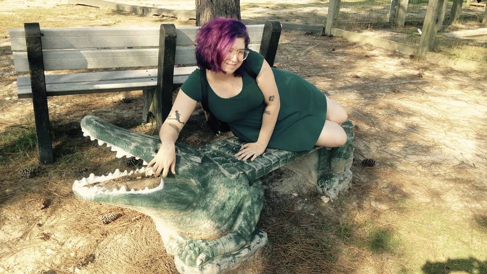 guest friend avery moore on a gator statue at a Louisiana gator farm