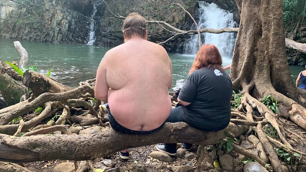 Jason and his mom sitting on a log at a hawaii watering hole