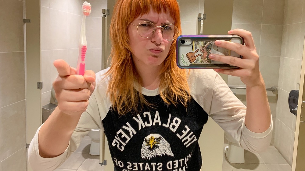 emily taking a bathroom mirror selfie with her toothbrush