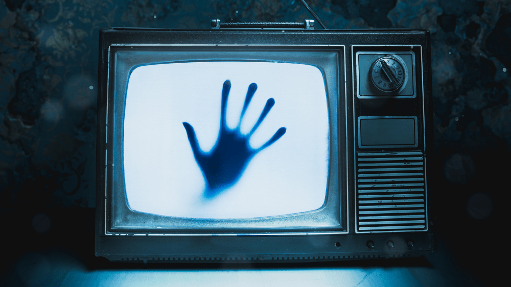 Scary movie hand on a old tv screen