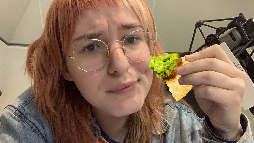 Emily holding up a chip and guac to her dimple