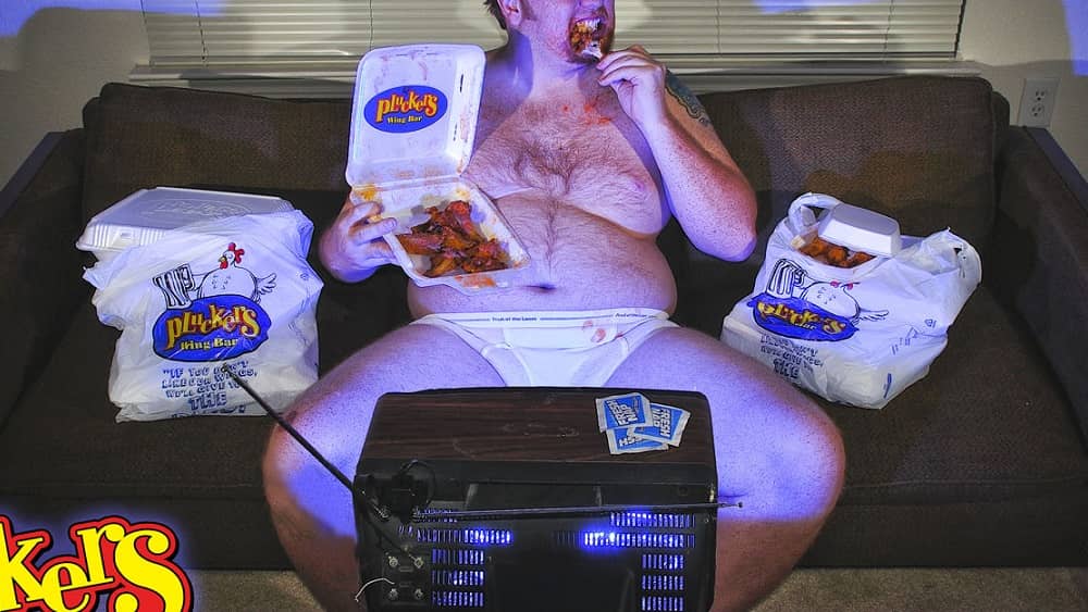 Jason in his underwear in front of the TV eating Pluckers wings
