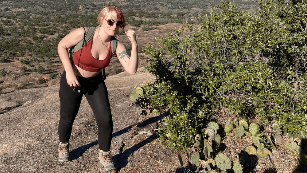 Emily flexing next to a cactus on Enchanted Rock