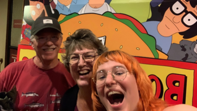 Emily and her parents standing in front of Bobs Burger sign