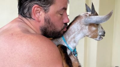 shirtless nick trying to kiss a goat