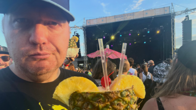 Jason standing in front of a riot fest stage with a pineapple drink