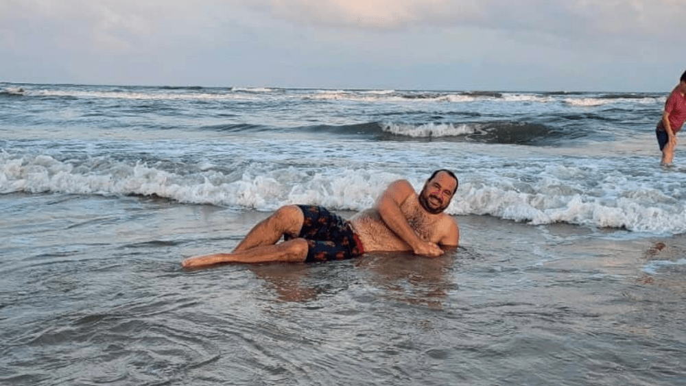 Nick laying in the ocean on the beach.