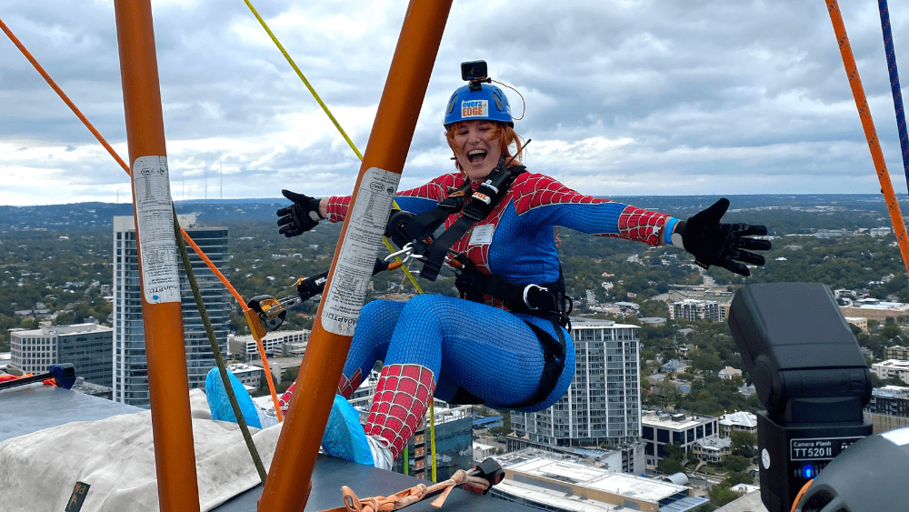 Emily is in a Spiderman costume repelling down the side of a building