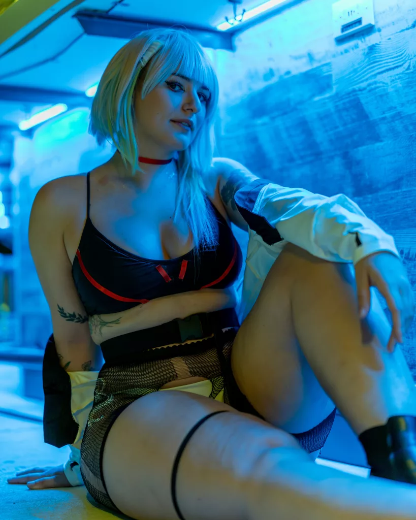 Emily posing under neon lights in a cosplay of Lucy from Cyber Punk