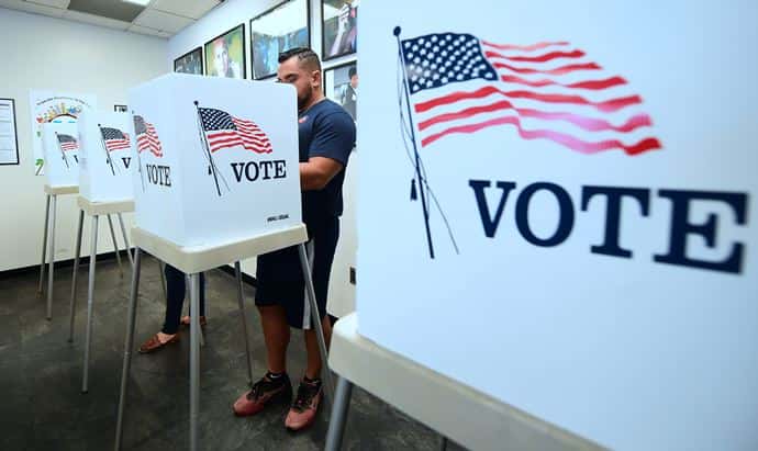 Person at a voting booth with voting booths on either side of him.