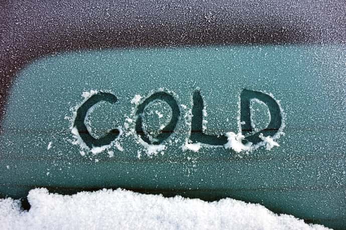 The word "COLD" scraped through frost on a car windshield